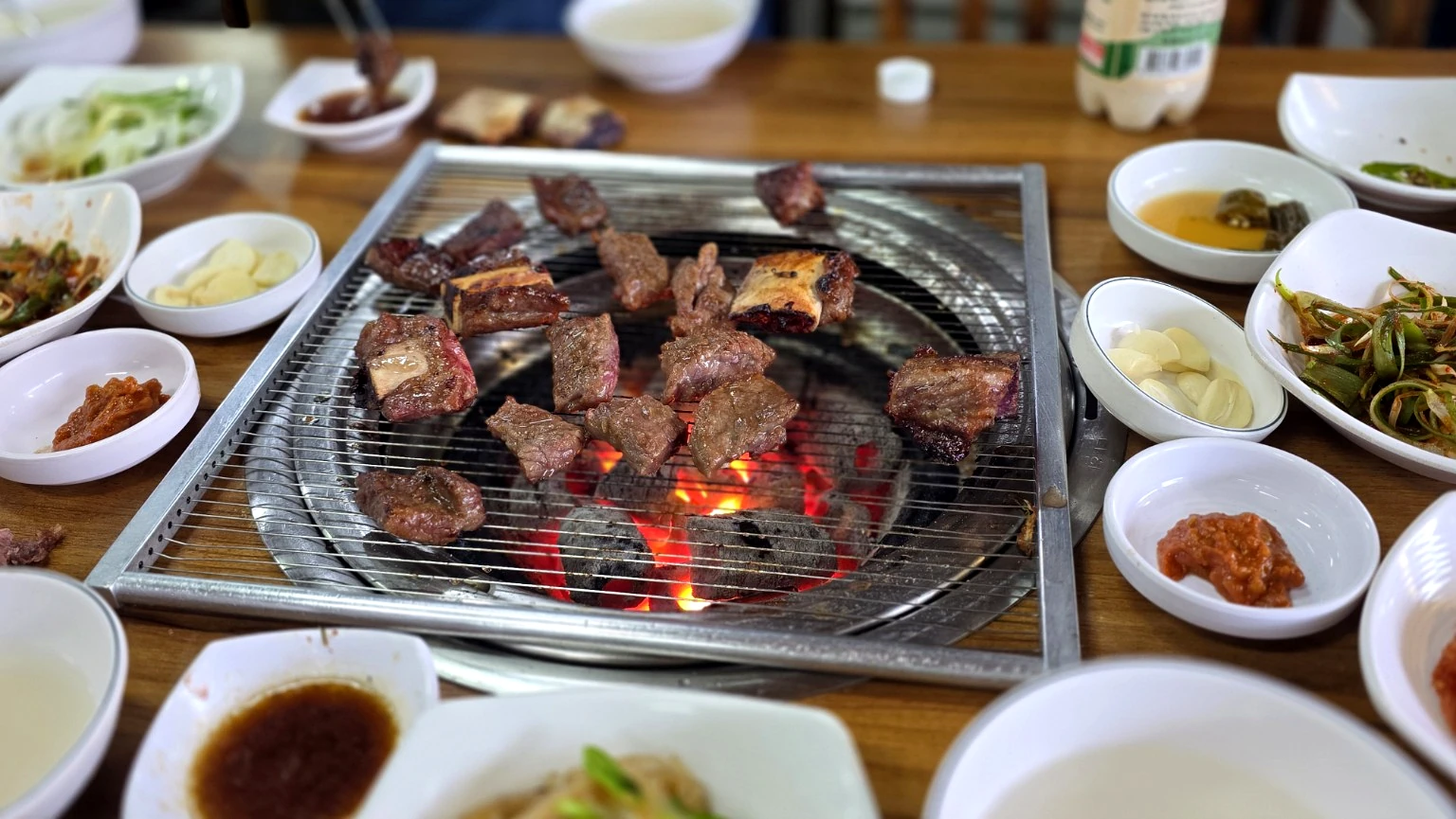 Idong galbi beef ribs and side dishes arranged on a Korean barbecue table before eating.