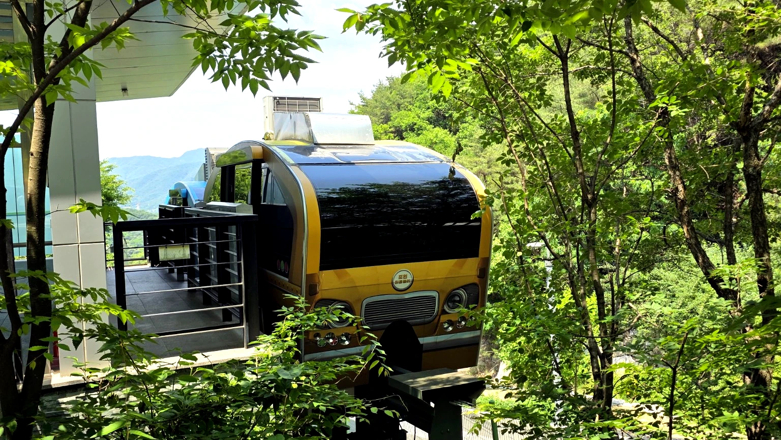 Monorail car climbing the forested hillside toward the upper park.