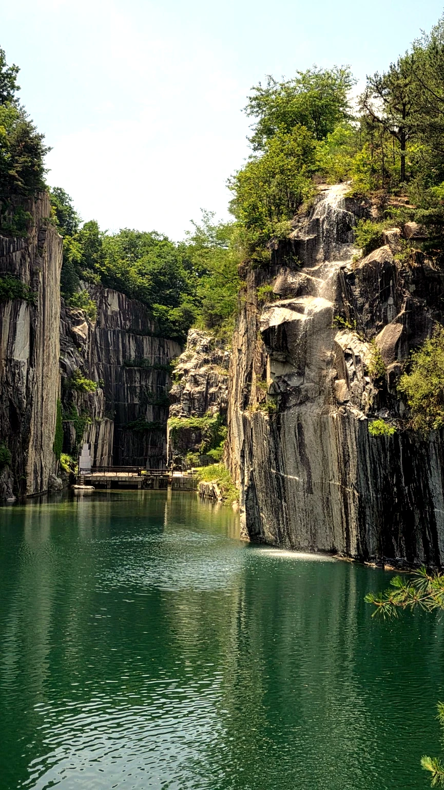 Artificial waterfall flowing beside Cheonjuho Lake and vertical granite cliffs.